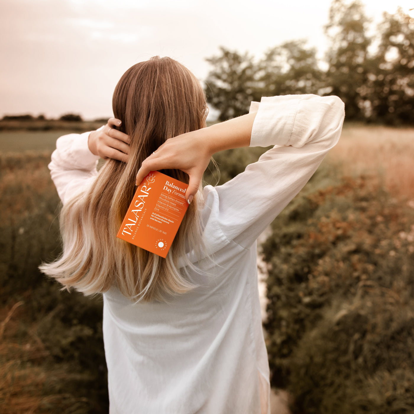 Frau in der Natur die das Talasar Produkt Balanced Day in der Hand hält.